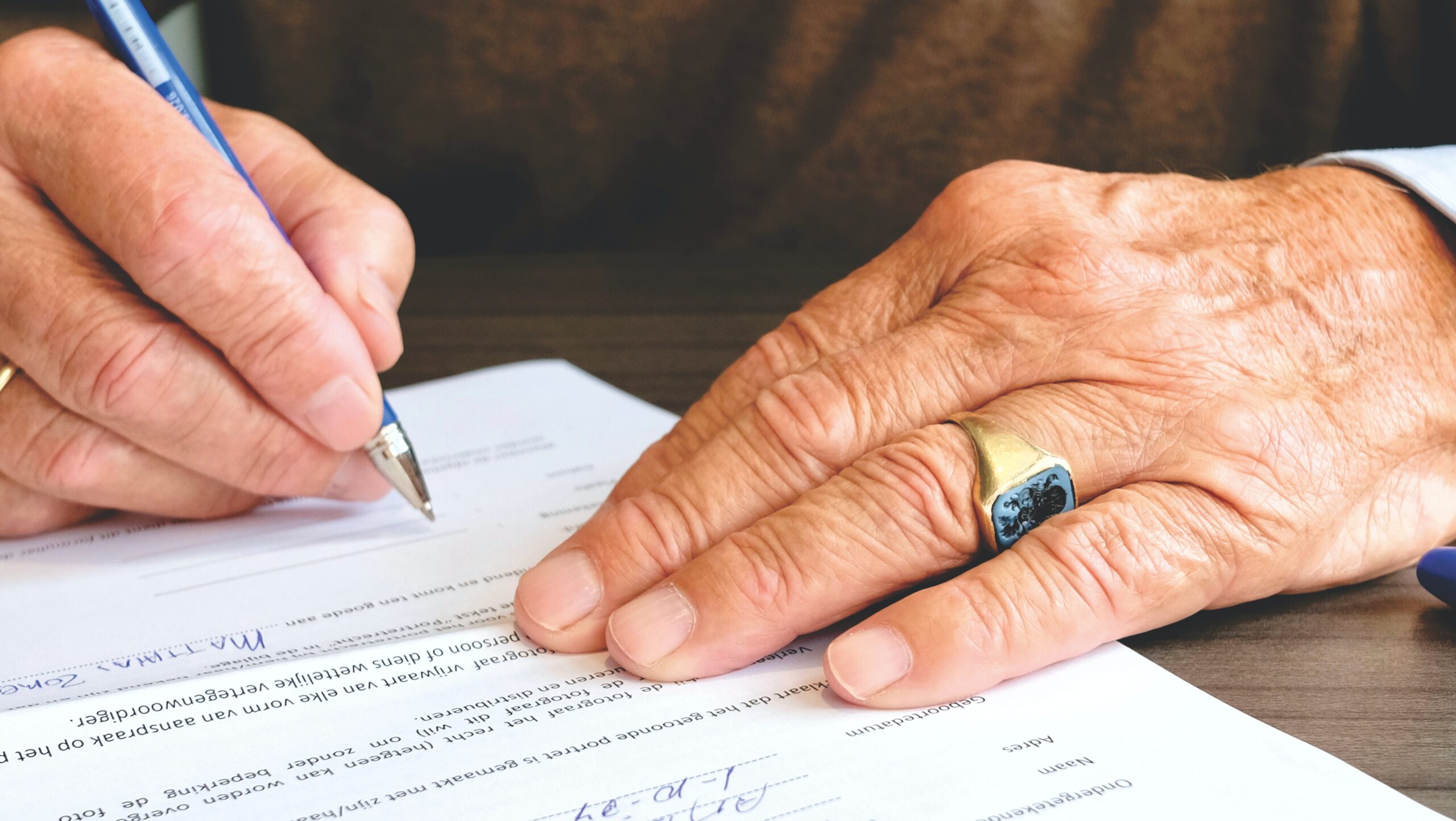 Starszy mężczyzna podpisuje akt notarialny darowizny w kancelarii
